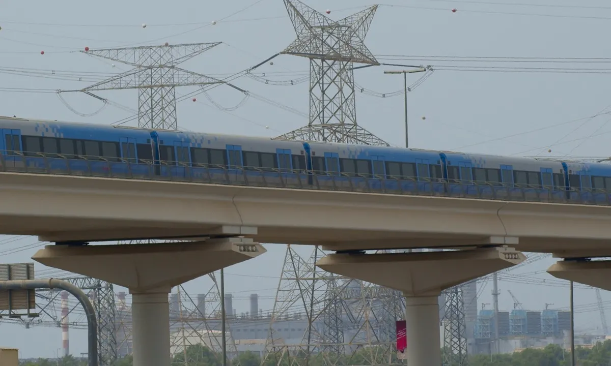 Dubai Metro train arriving at an elevated station with the Deira skyline behind